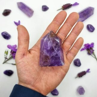 amethyst single point 101-150g on hand with crystal background