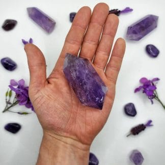 amethyst double point 101-150g on hand with crystals in background