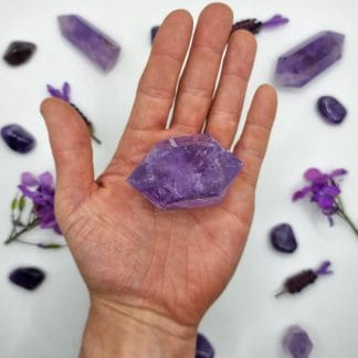 amethyst double point 76-100g on hand with crystals in background