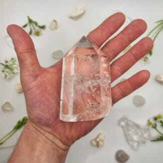 Clear Quartz crystal on hand with crystals in background